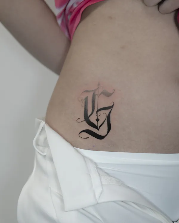 Gothic blackletter initial hip feminine tattoo Bangkok