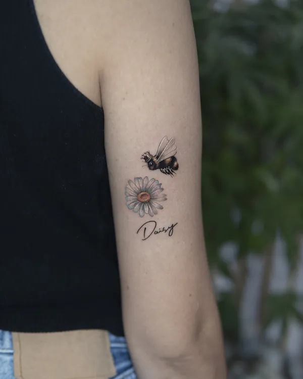 Bee and daisy with name script arm feminine tattoo Bangkok