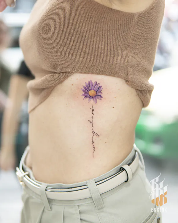 Purple daisy with script text ribs feminine girly tattoo Bangkok