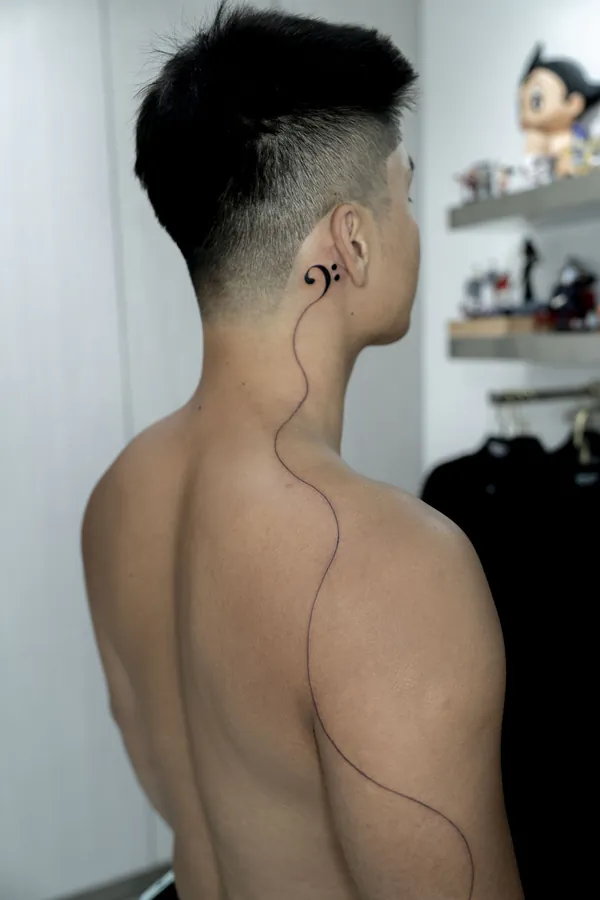 Bass clef with flowing line neck fine line tattoo Bangkok