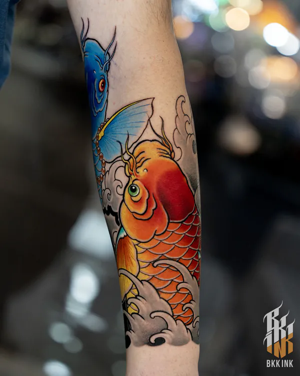 Blue horned creature and orange koi forearm Japanese tattoo Bangkok