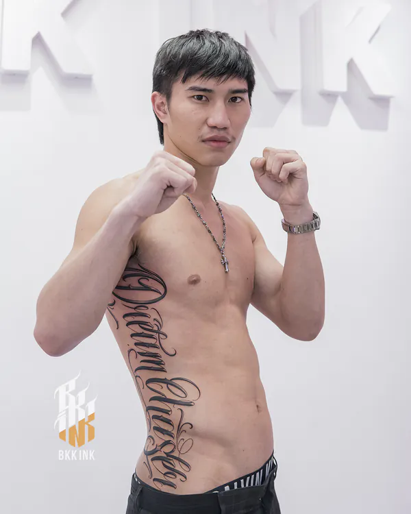 Fine cursive script side ribs lettering tattoo Bangkok