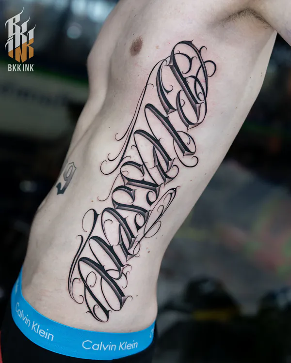 Flowing cursive script rib cage lettering tattoo Bangkok