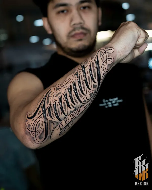Elegant cursive script inner forearm lettering tattoo Bangkok