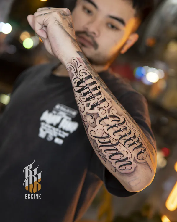 Cursive banner script forearm lettering tattoo Bangkok
