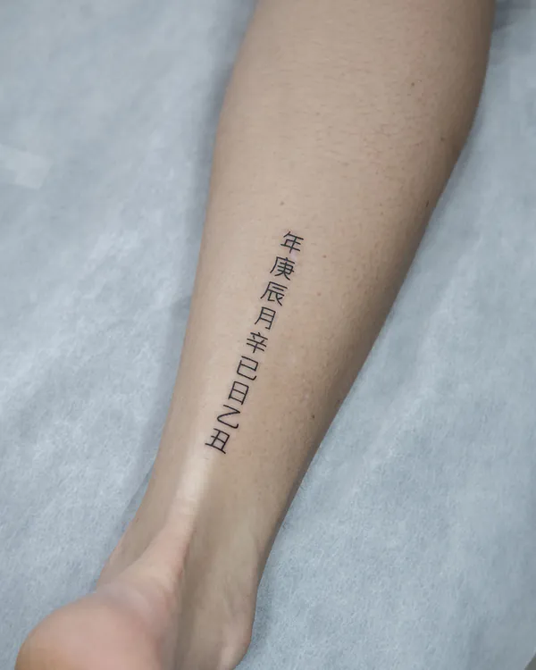 Fine line vertical characters calf lettering tattoo Bangkok