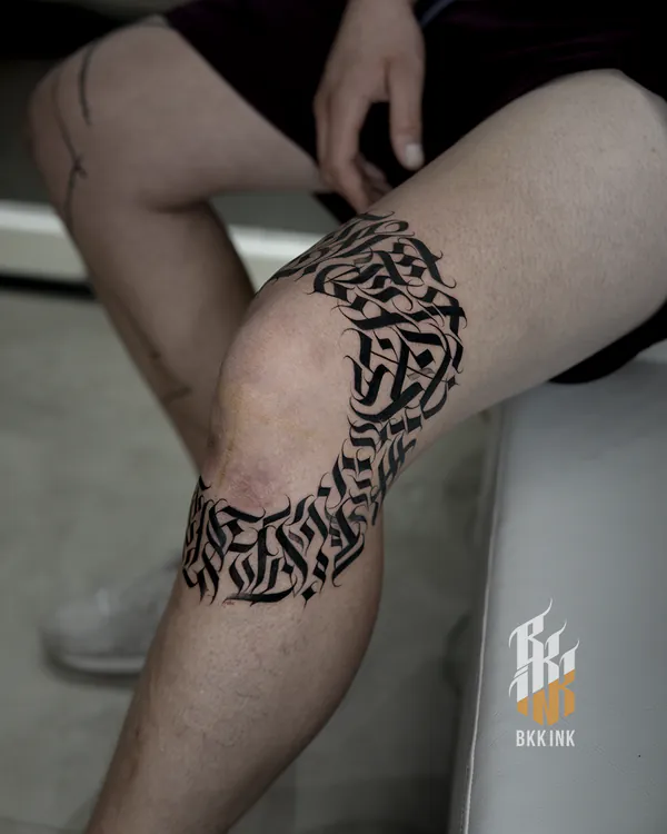 Tribal calligraphy wraparound knee lettering tattoo Bangkok