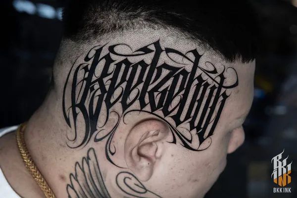 Gothic blackletter script forehead lettering tattoo Bangkok