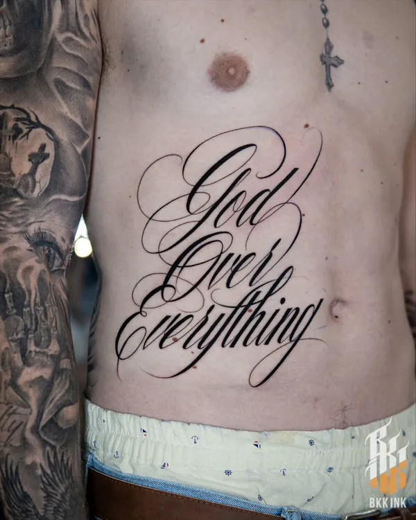 Flowing cursive script stomach lettering tattoo Bangkok