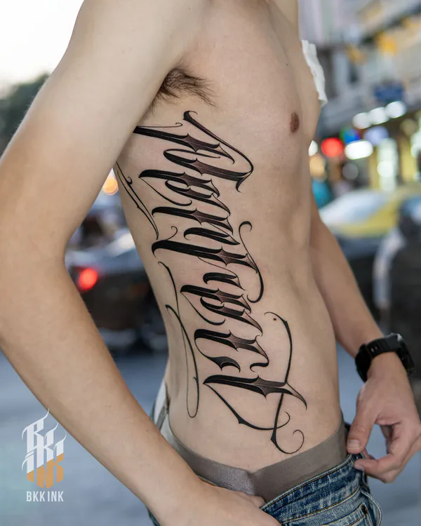 Vertical chicano script rib lettering tattoo Bangkok