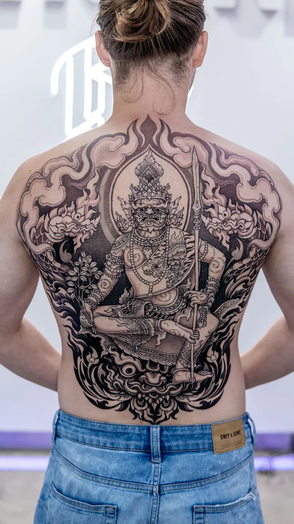 Seated yaksha deity holding spear on flame throne back Neo-Thai tattoo Bangkok