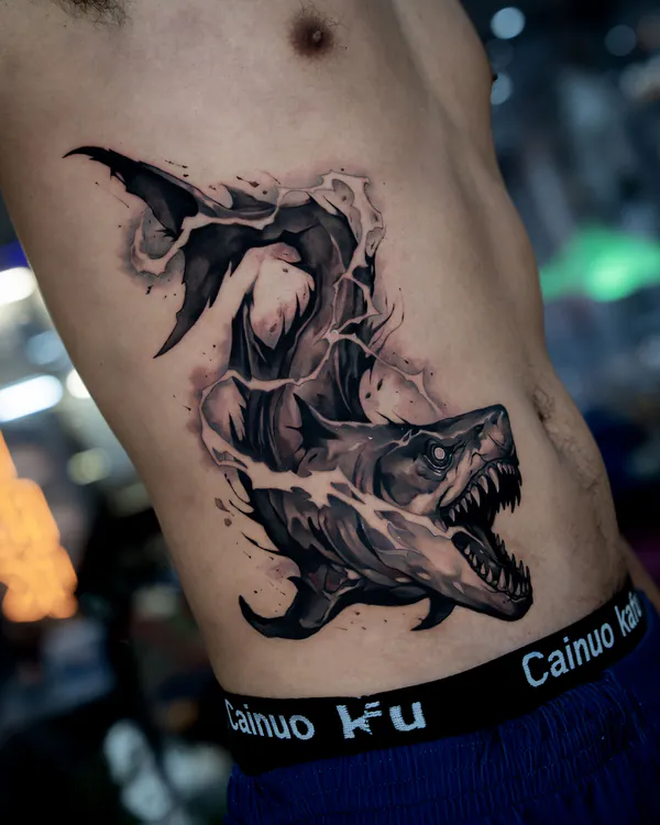 Black and grey shark bursting through skin ribs neo-traditional tattoo Bangkok