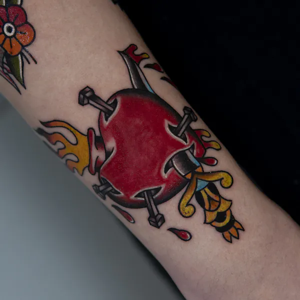 Heart pierced with nails and flames forearm old school tattoo Bangkok