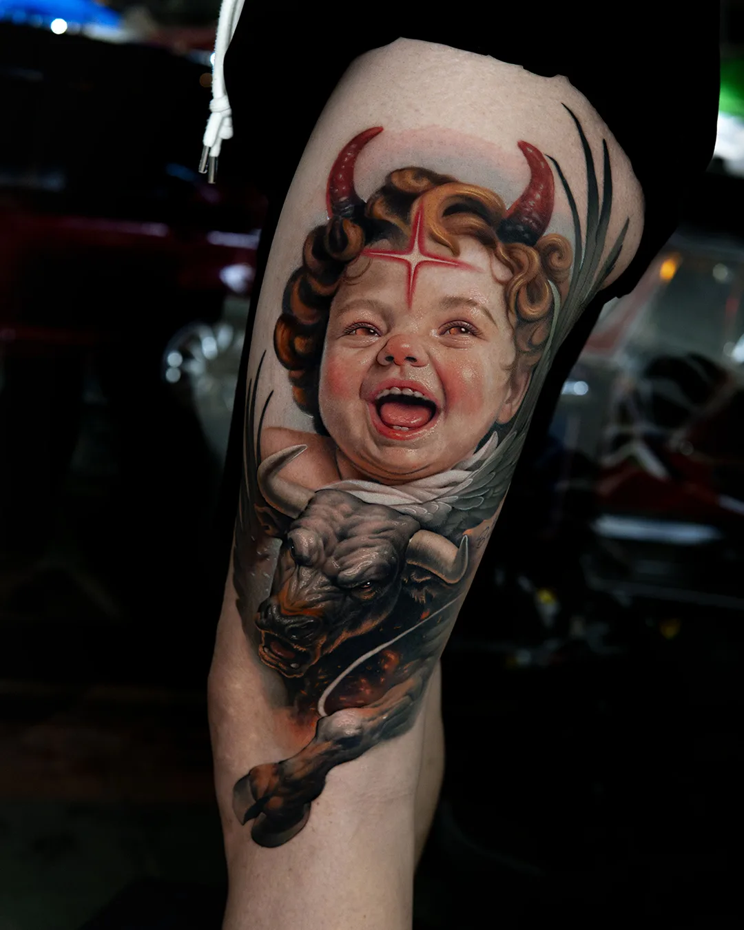 Colour laughing baby with devil horns and bull thigh realistic tattoo Bangkok