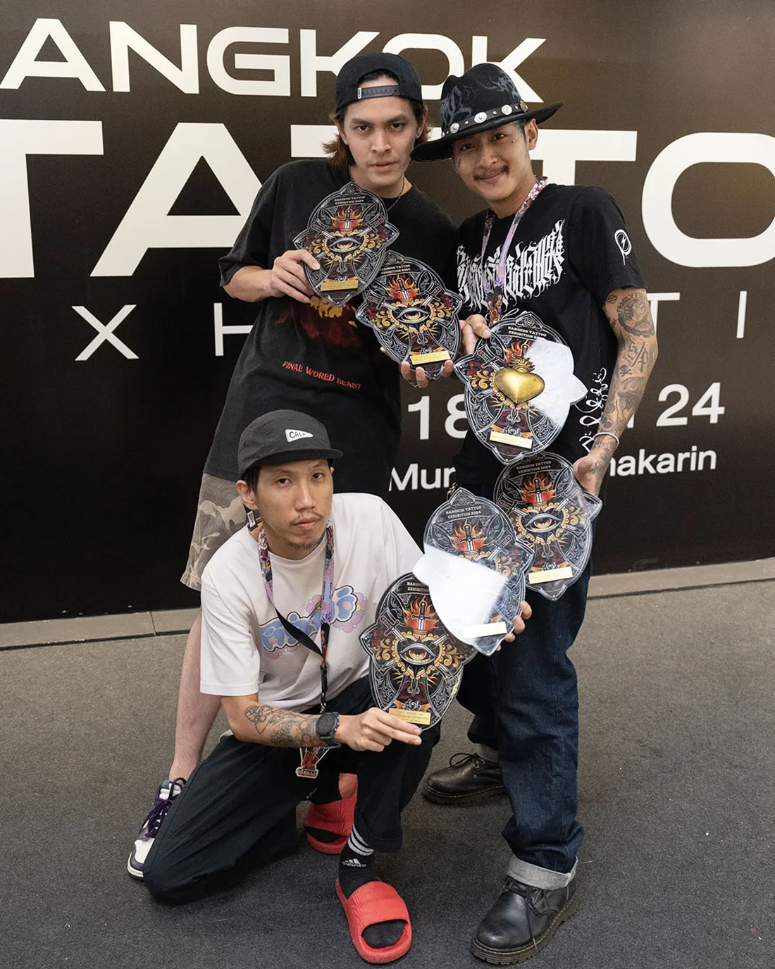 Three BKK INK artists holding seven award plaques at Bangkok Tattoo Exhibition 2024