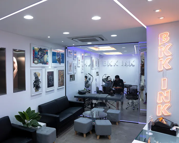 BKK INK studio interior with client lounge, framed artwork and glass-walled tattoo work room