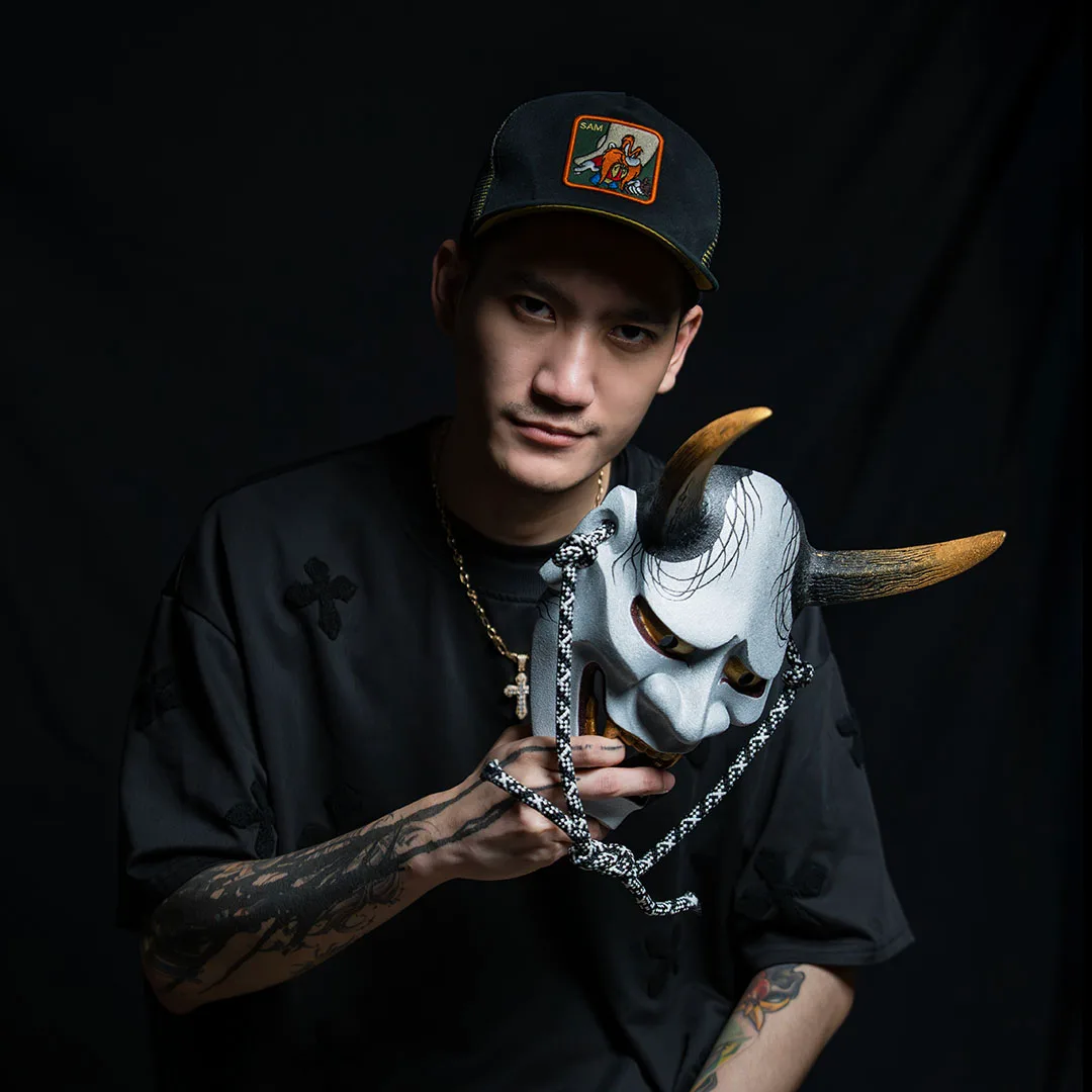 Vay, neo-traditional colour tattoo artist at BKK INK Bangkok, holding a hannya mask